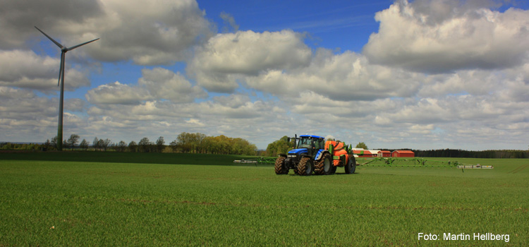 En traktor kör på åkermarken och sprutar bekämpningsmedel.