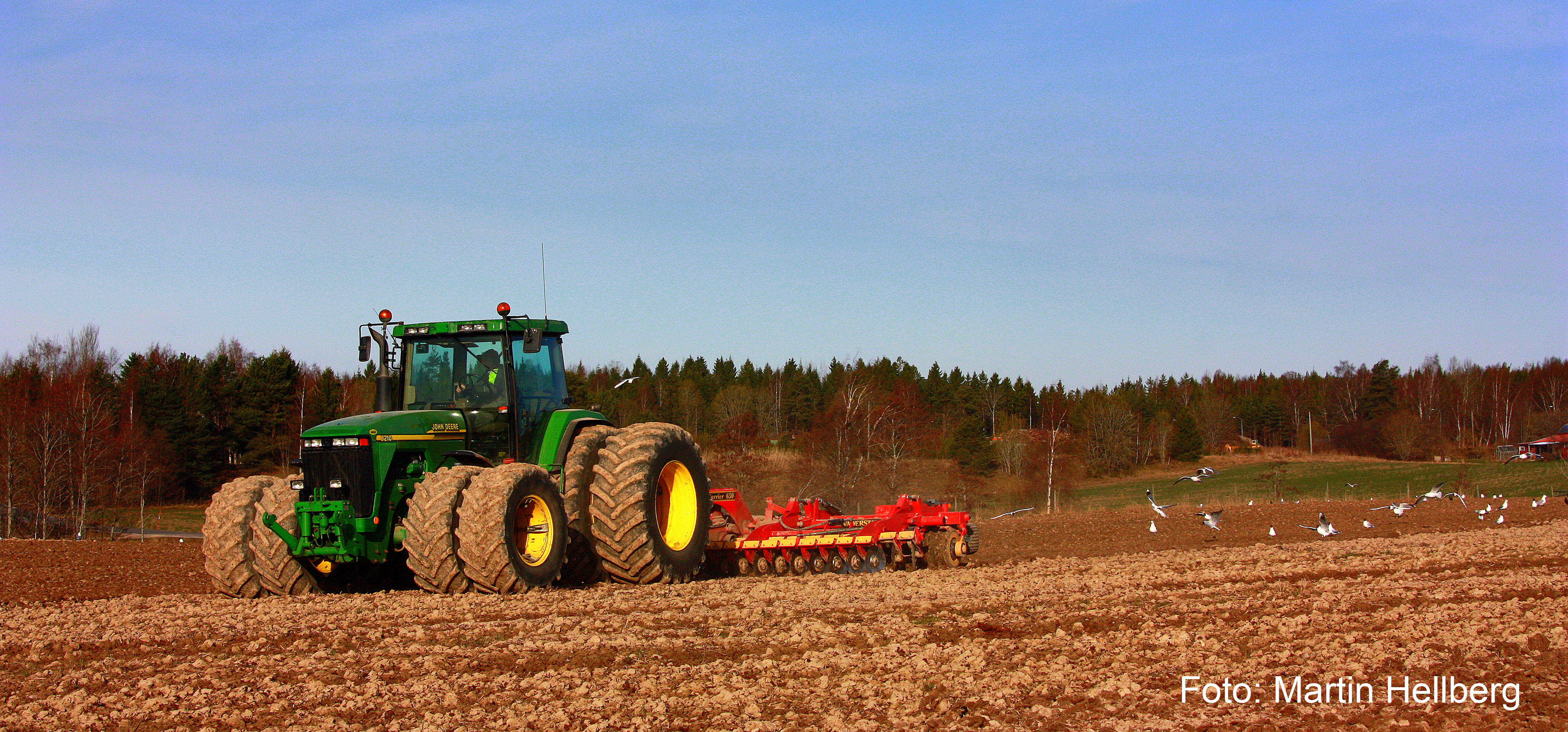 Bilden visar en traktor på ett fält.