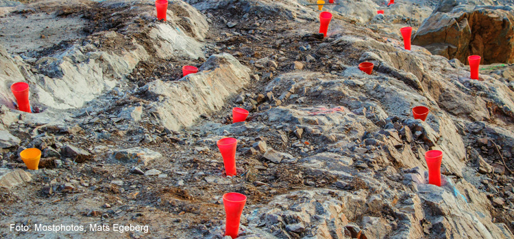 Bilden visar röda och gula trattar nedsatta i berget inför sprängning.