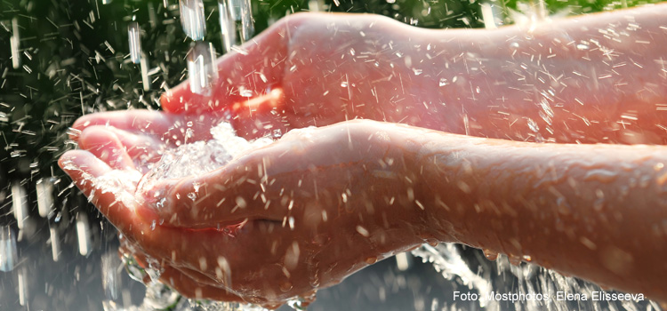 Bilden visar en person som håller sina händer under rinnande vatten.